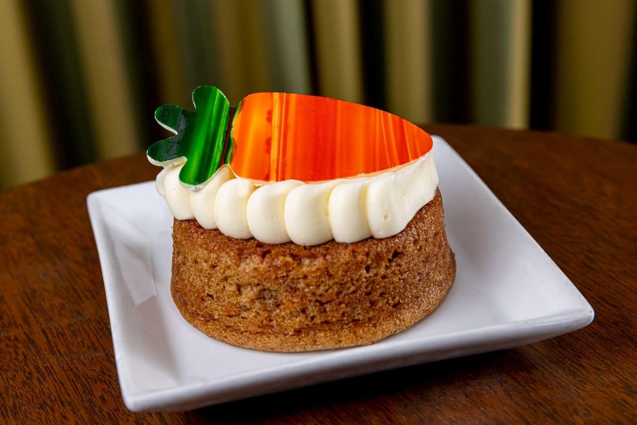 Carrot cake with cream cheese icing and white chocolate carrot garnish
